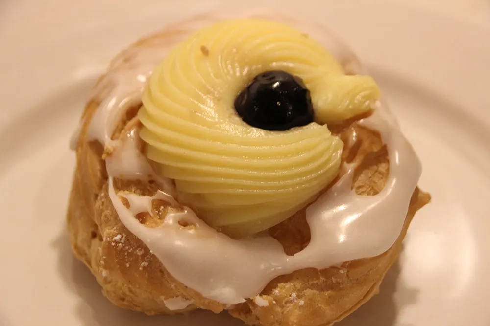 Custard fills the zeppole and topped with a sour cherry